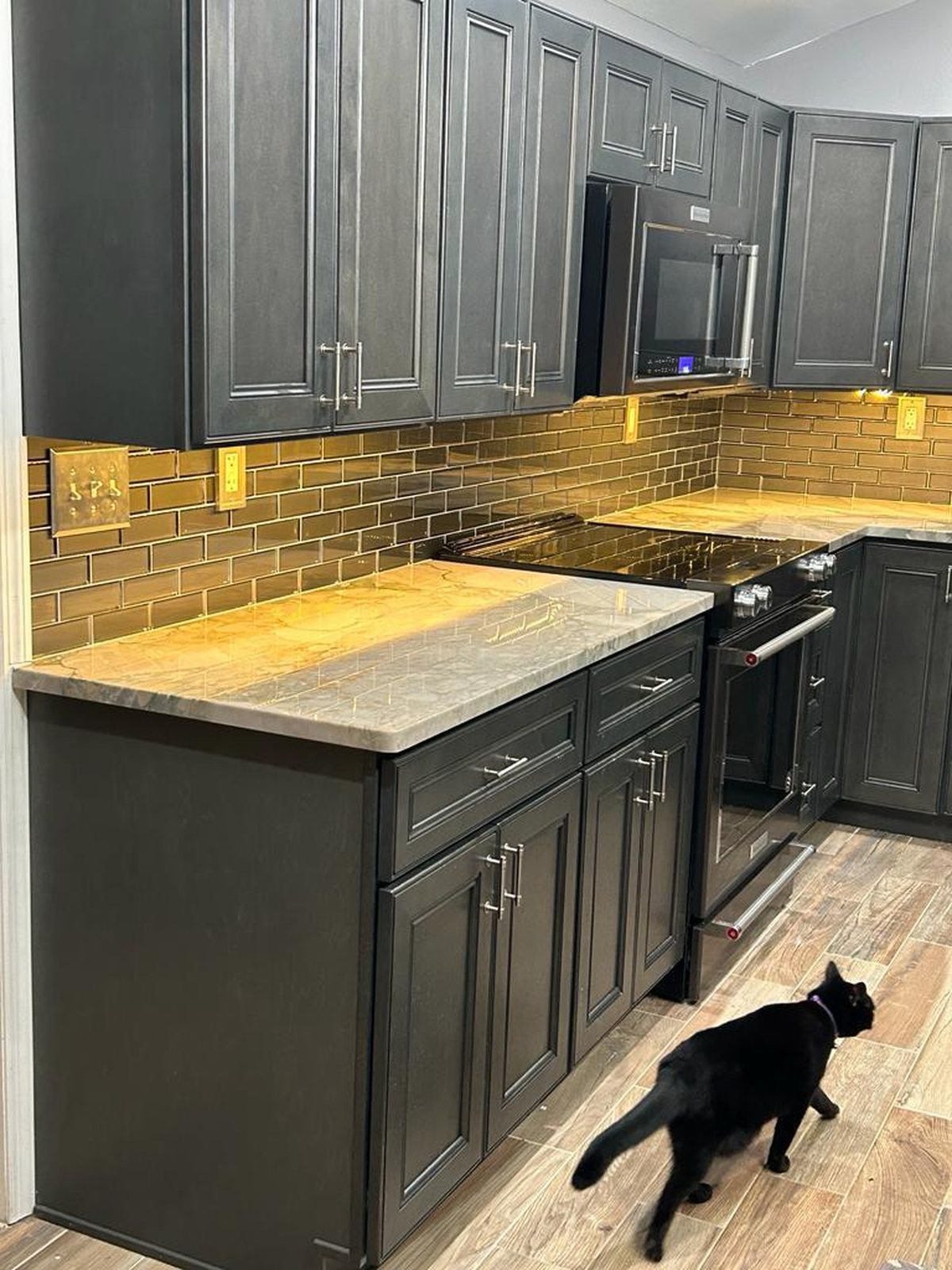 Charcoal kitchen with bronze glass subway backsplash and wood-look plank flooring