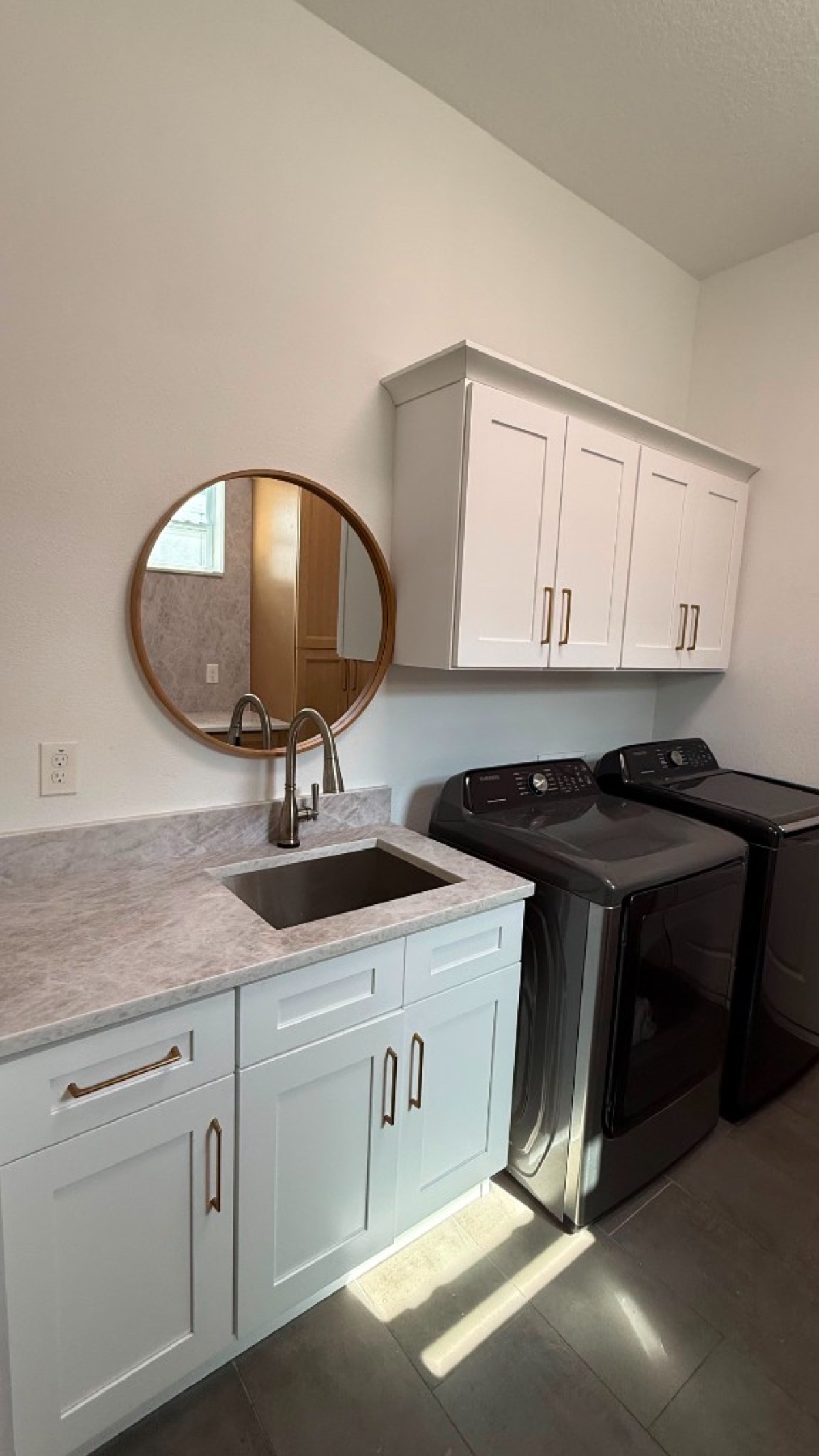 Laundry with white Shaker cabinets, gold pulls, a marble-look counter, black sink and charcoal Samsung washer and dryer