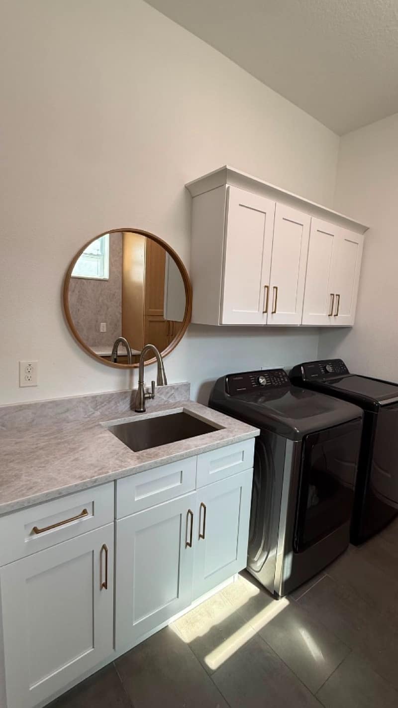 Laundry with white Shaker cabinets, gold pulls, a marble-look counter, black sink and charcoal Samsung washer and dryer