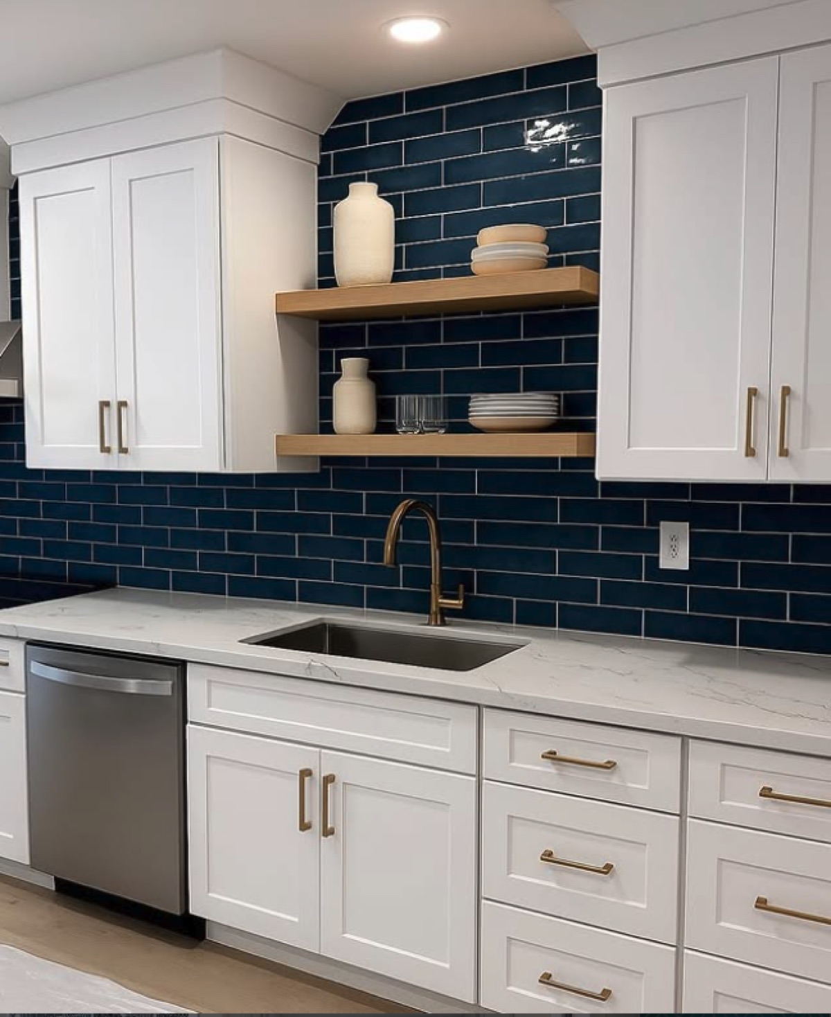 Kitchen with a navy subway-tile backsplash, white Shaker cabinets, marble counters and gold fixtures