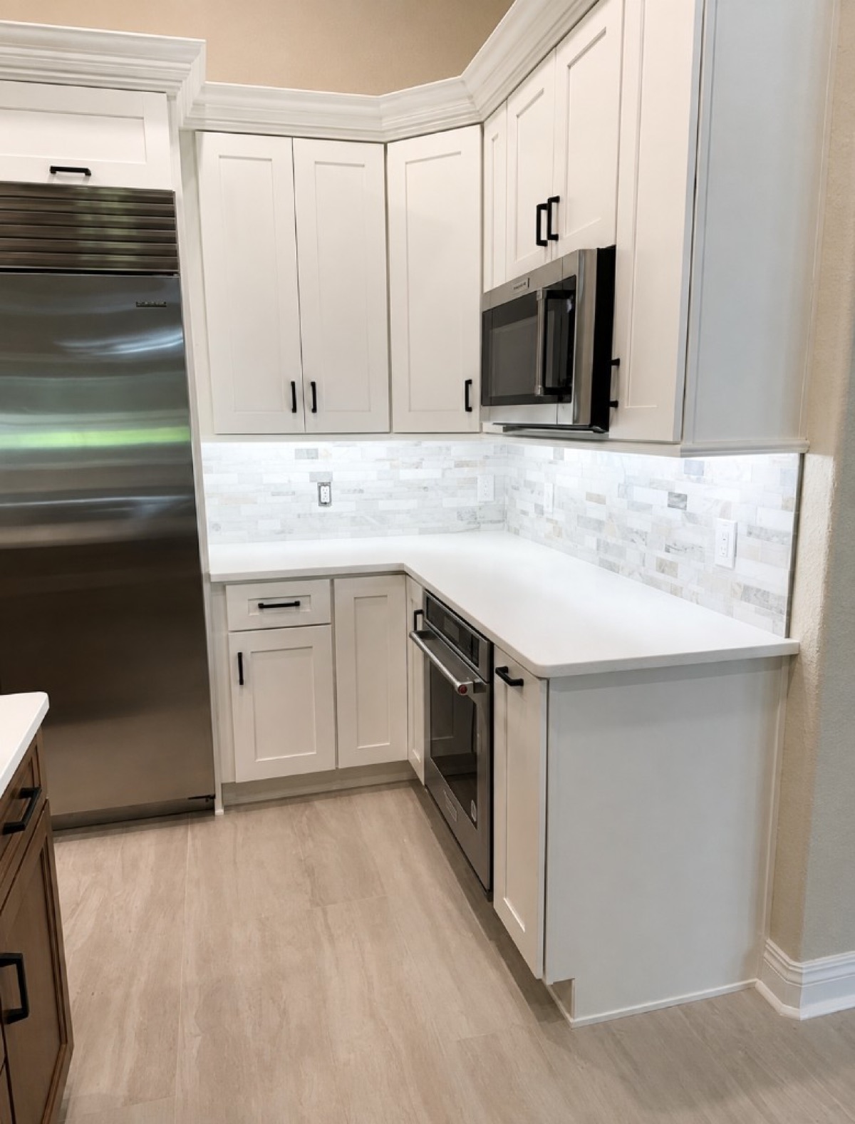 White Shaker kitchen with marble mosaic backsplash, black hardware and stainless appliances