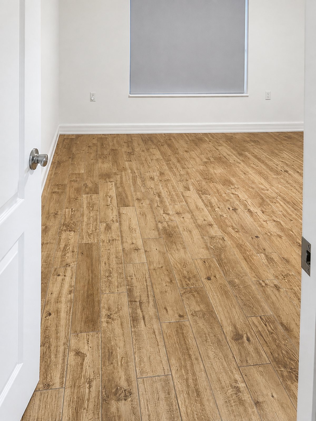 Newly installed wood-look luxury vinyl plank in an empty room with white baseboards